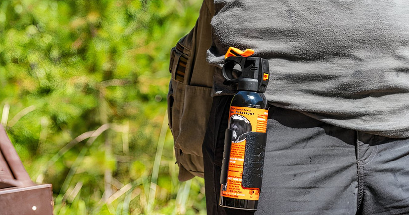 A traveler carrying bear spray while hiking