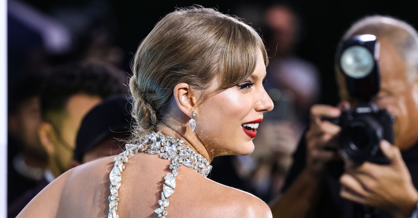 Taylor Swift smiling in front of cameras.