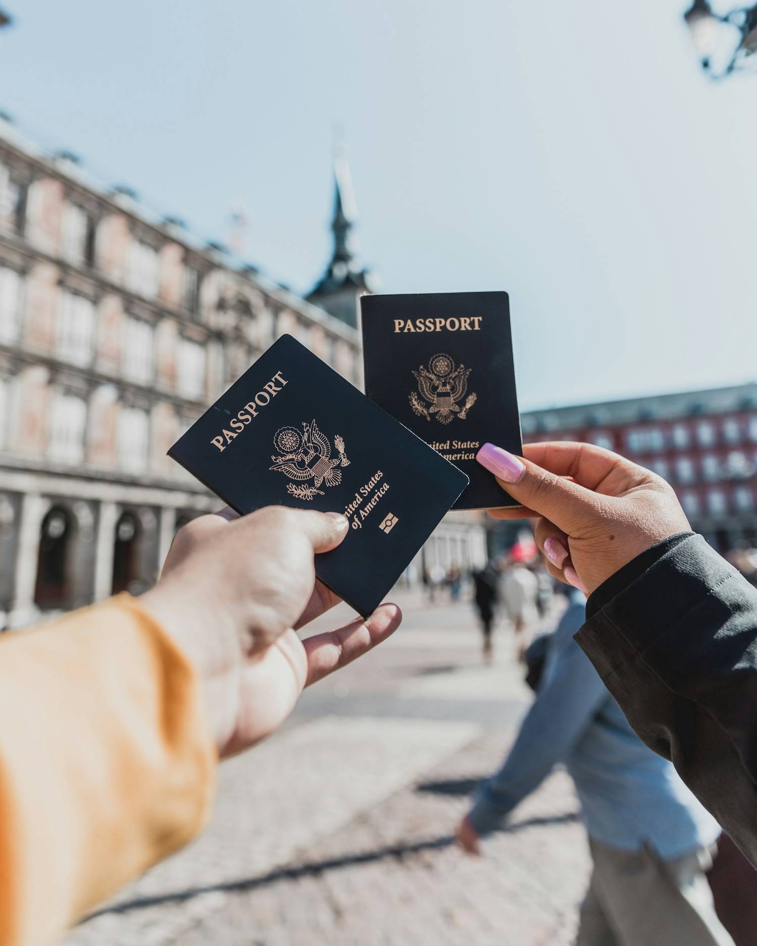 Two hands each holding a US passport up in front of scenery in Spain