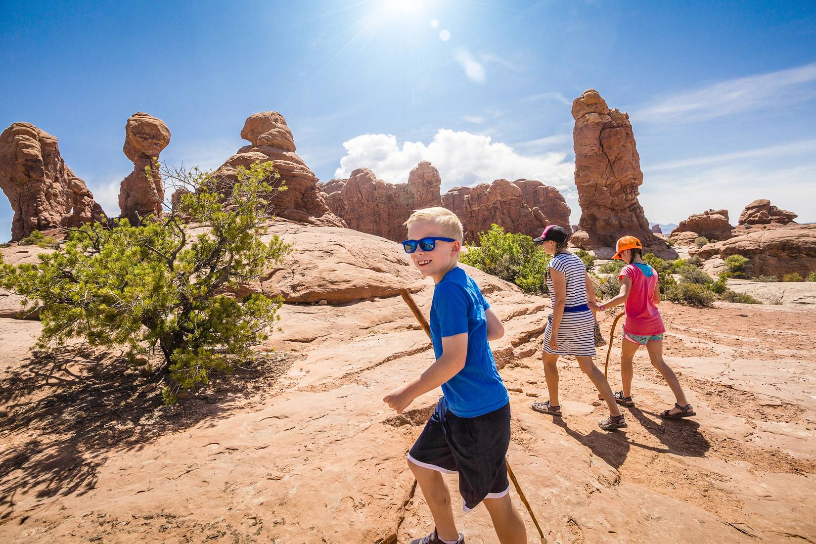 Happy family hiking together in the beautiful rock formations of Arches National Park. Walking along a scenic trail with large rock unique formations in the background — Photo