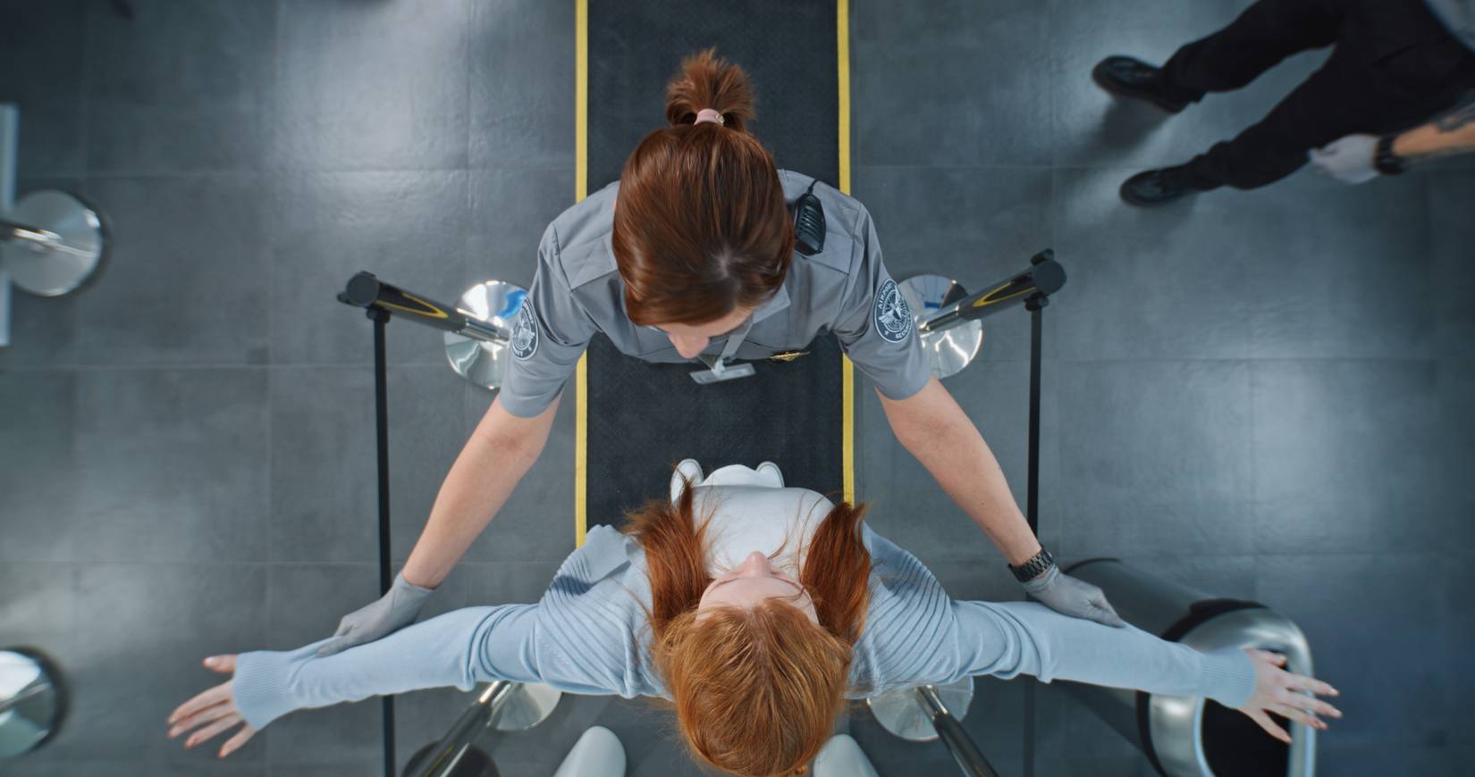 A top-down view of a woman being searched by TSA at airport security