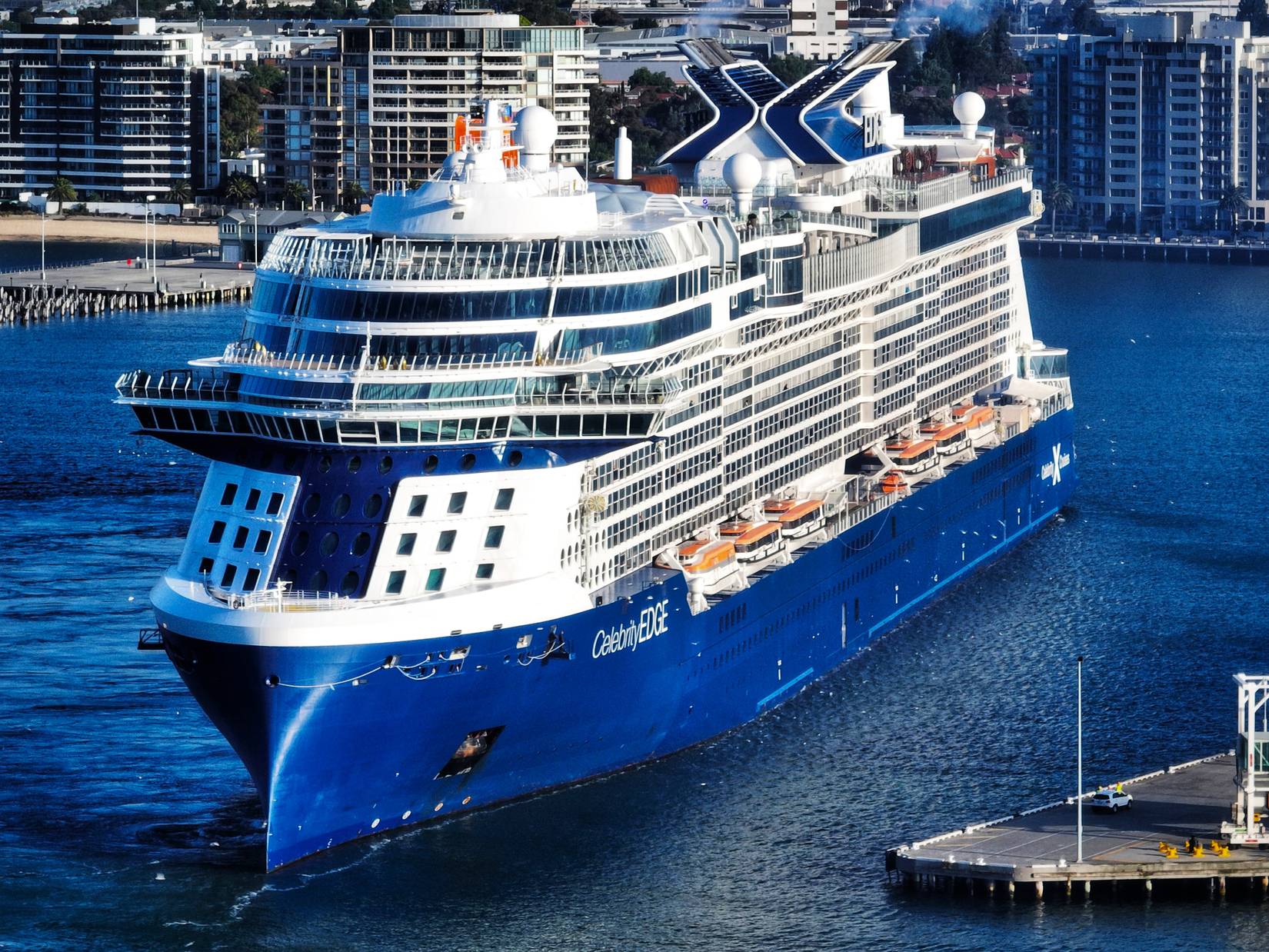 Celebrity Cruises ship, the Celebrity Edge, in the water near a port