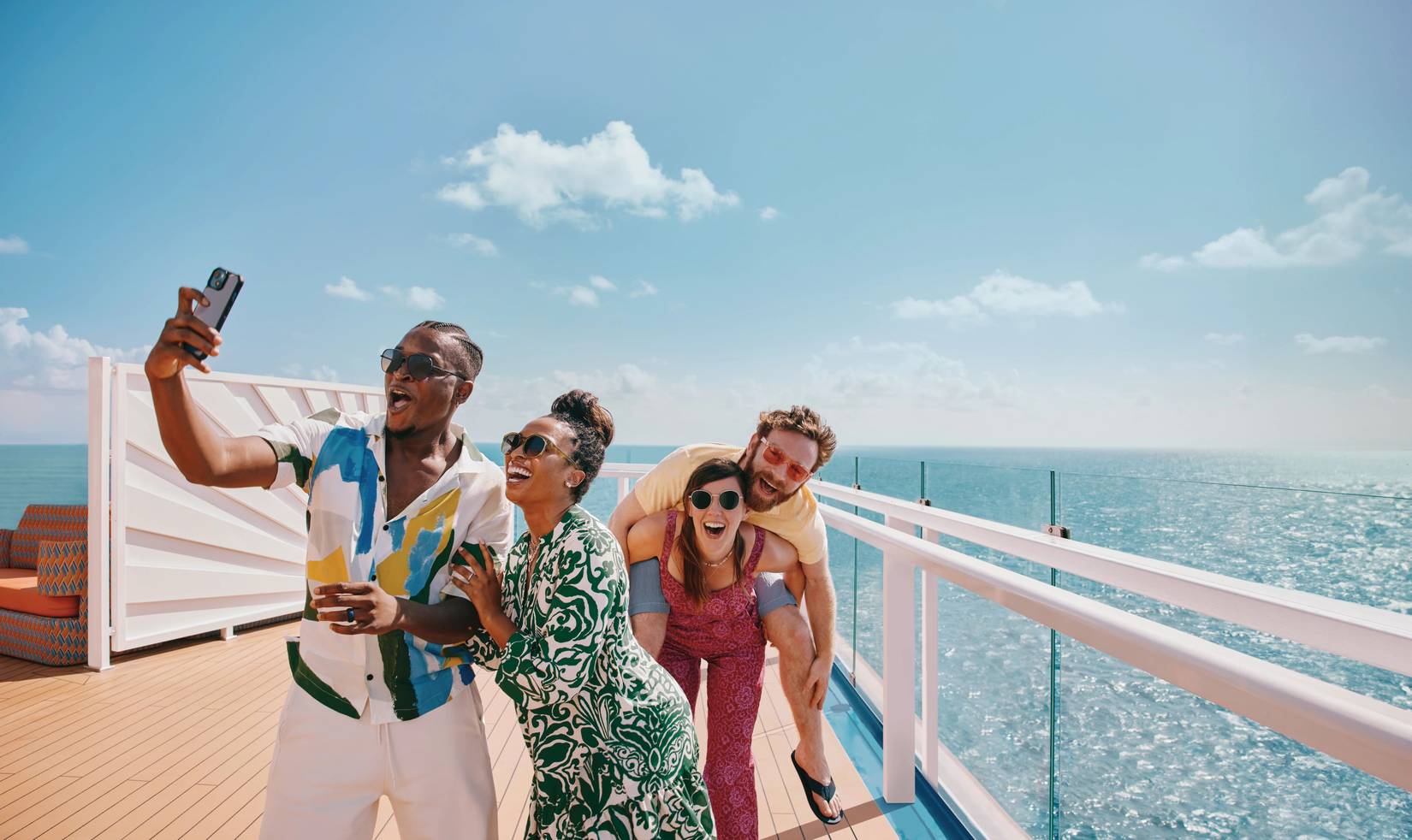 Carnival Cruise Line passengers pose for a selfie by the railing of a cruise ship on a sunny day