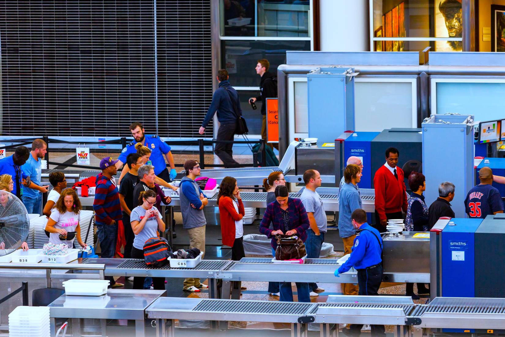 TSA agent at busy airport security checkpoint when tourists are checked