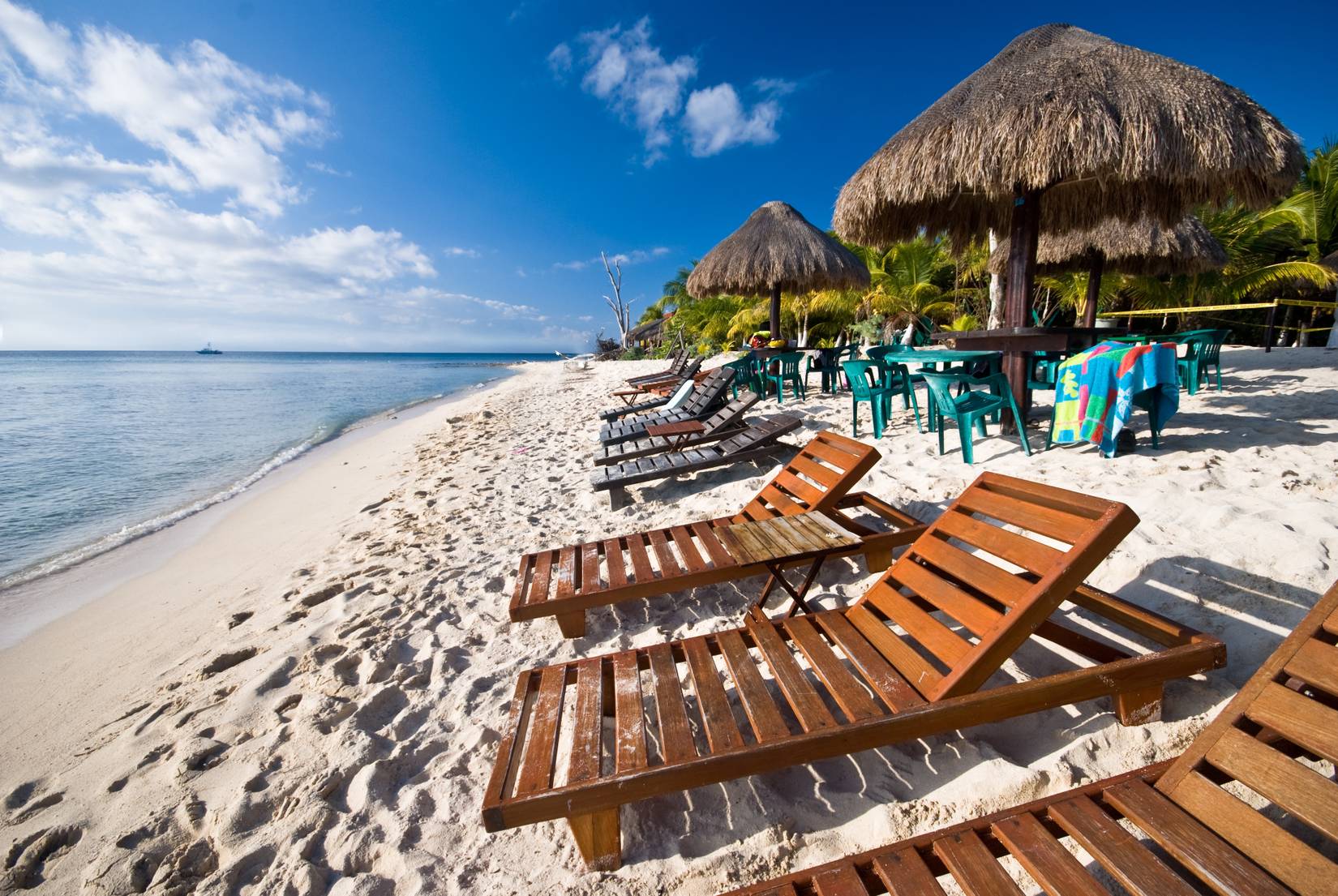 Wooden lounge chairs lined up on sunny beach in Cozumel, Mexico