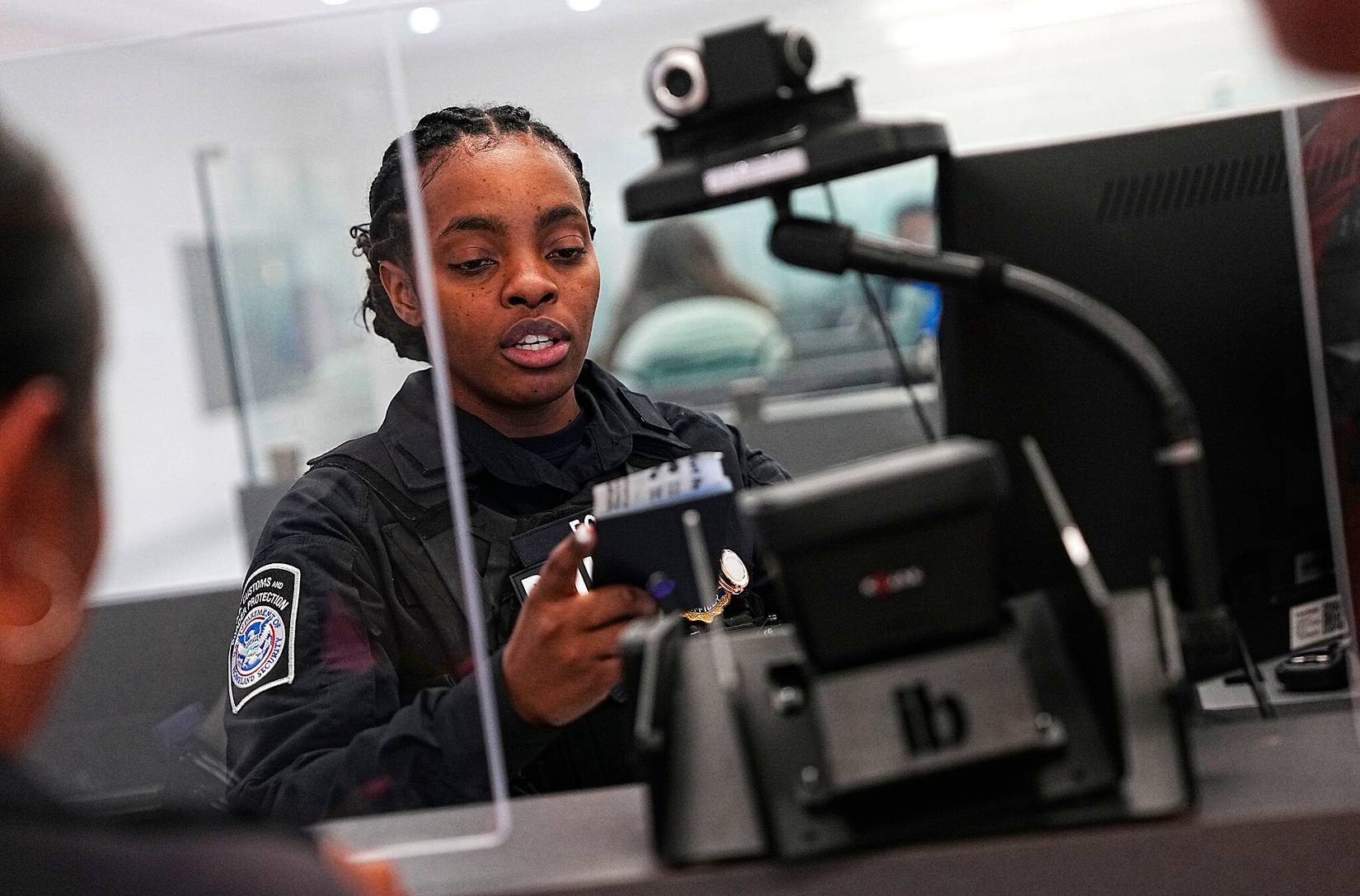 US Customs and Border Protection officer at an airport desk checking passports