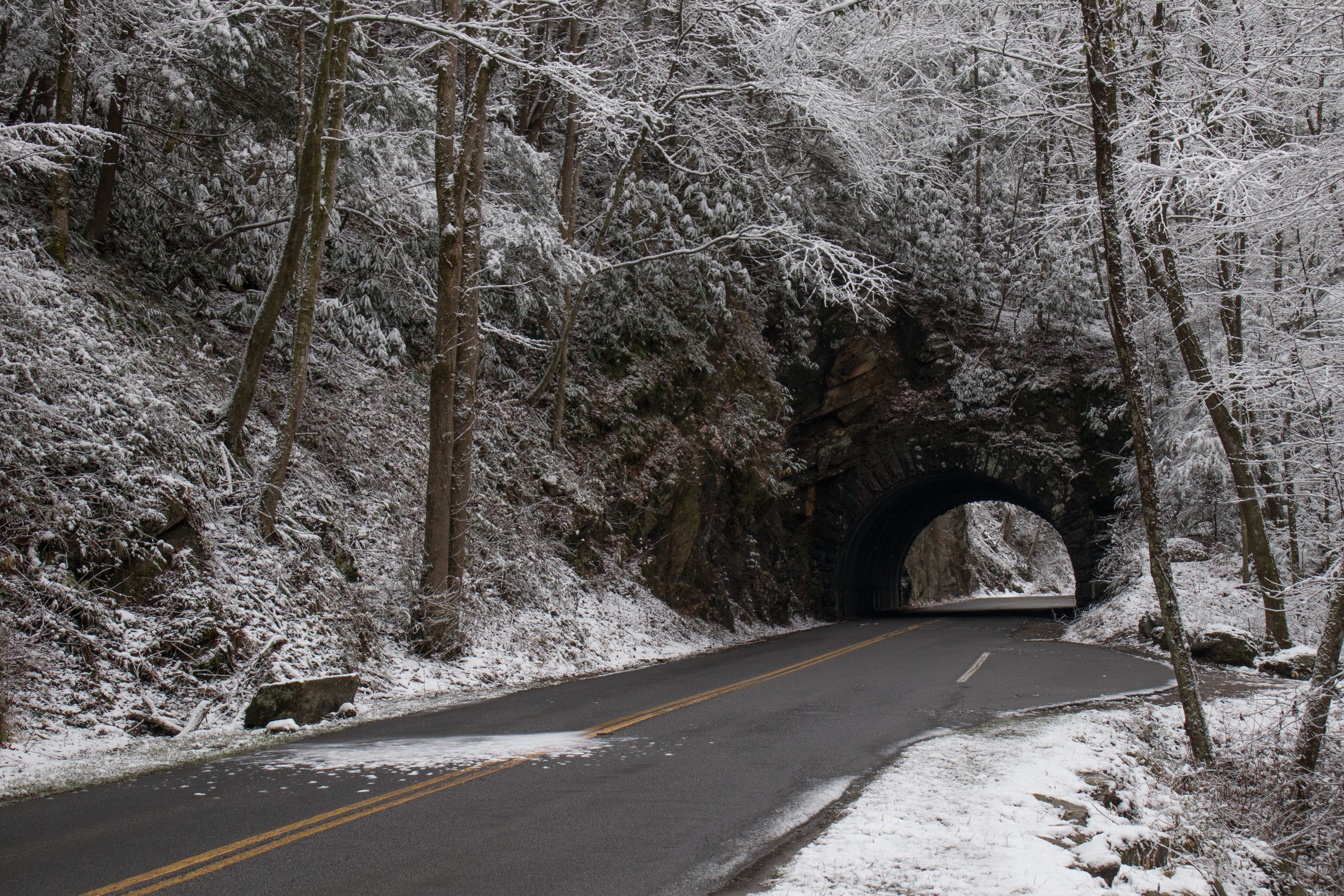 A view of a tunnel and curvy windy road through snow-covered woods in Great Smoky Mountains National Park, Tennessee, TN, USA.