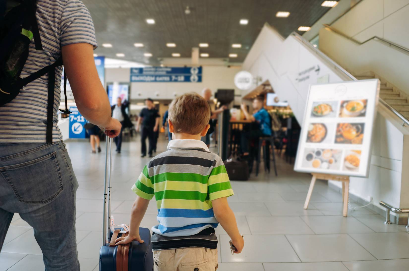 A father and son walking with a suticase through the airport