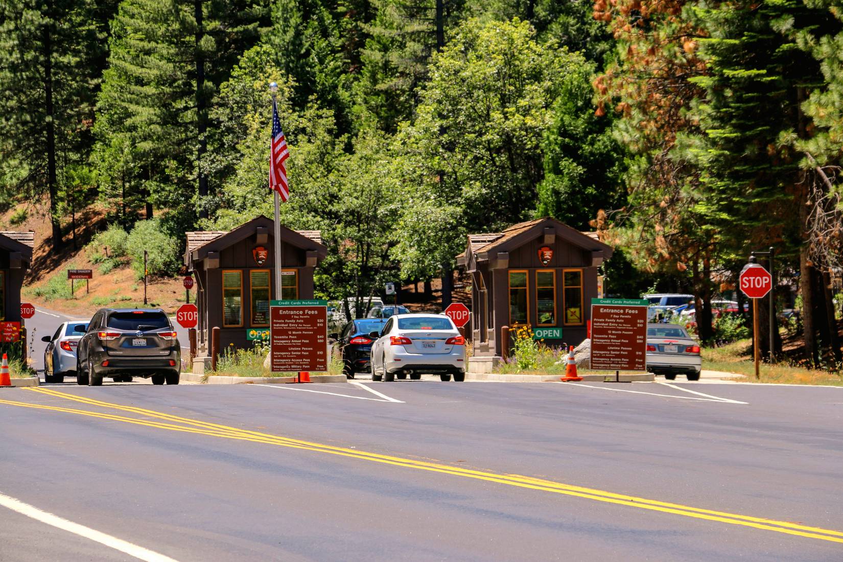 Ulaz u nacionalni park Yosemite. Automobili se približavaju ulaznim kabinama. U pozadini se vidi šuma.