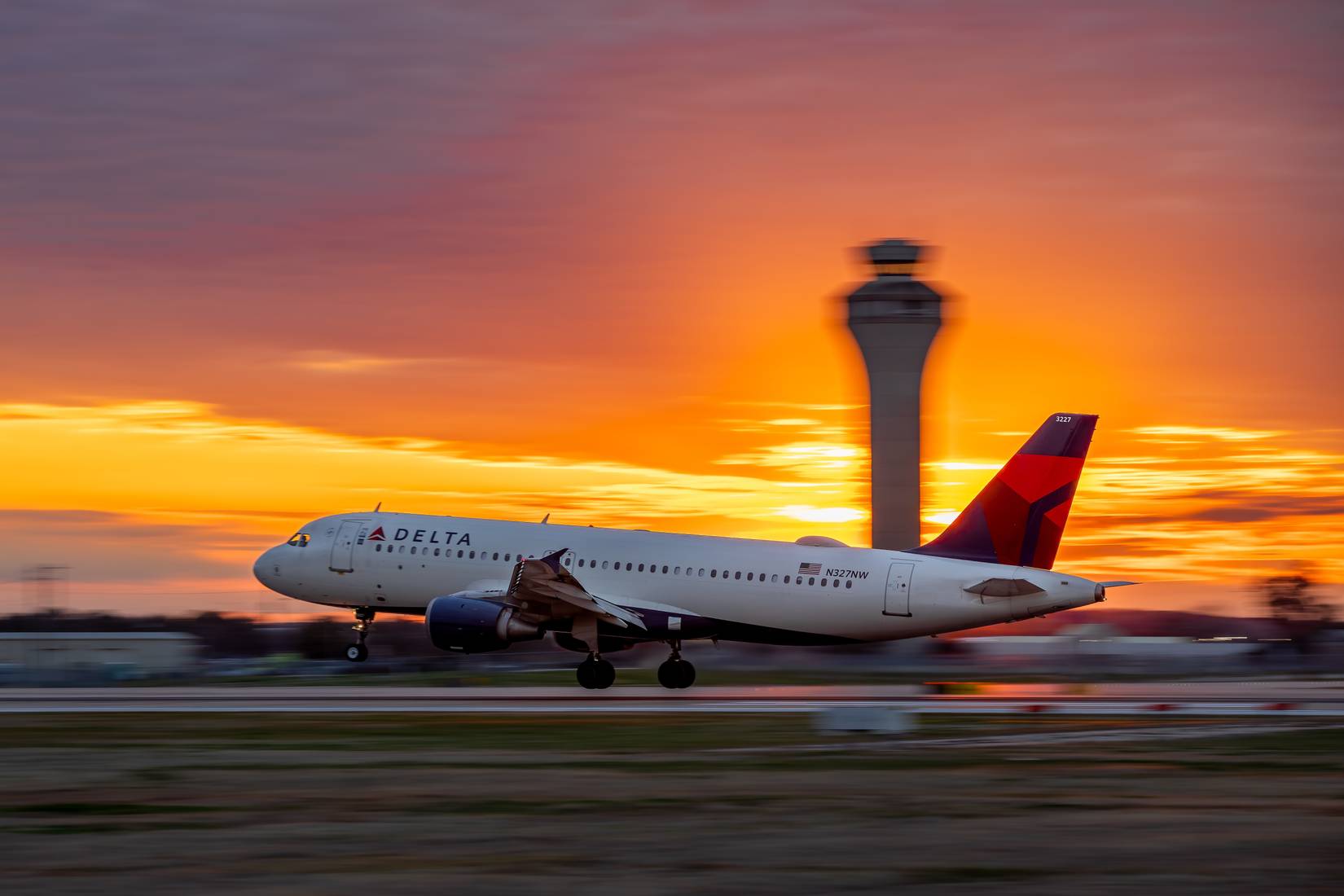 A Delta airplane takes off from Phoenix Sky Harbor Airport at sunset. The ATC tower can be seen in the background.