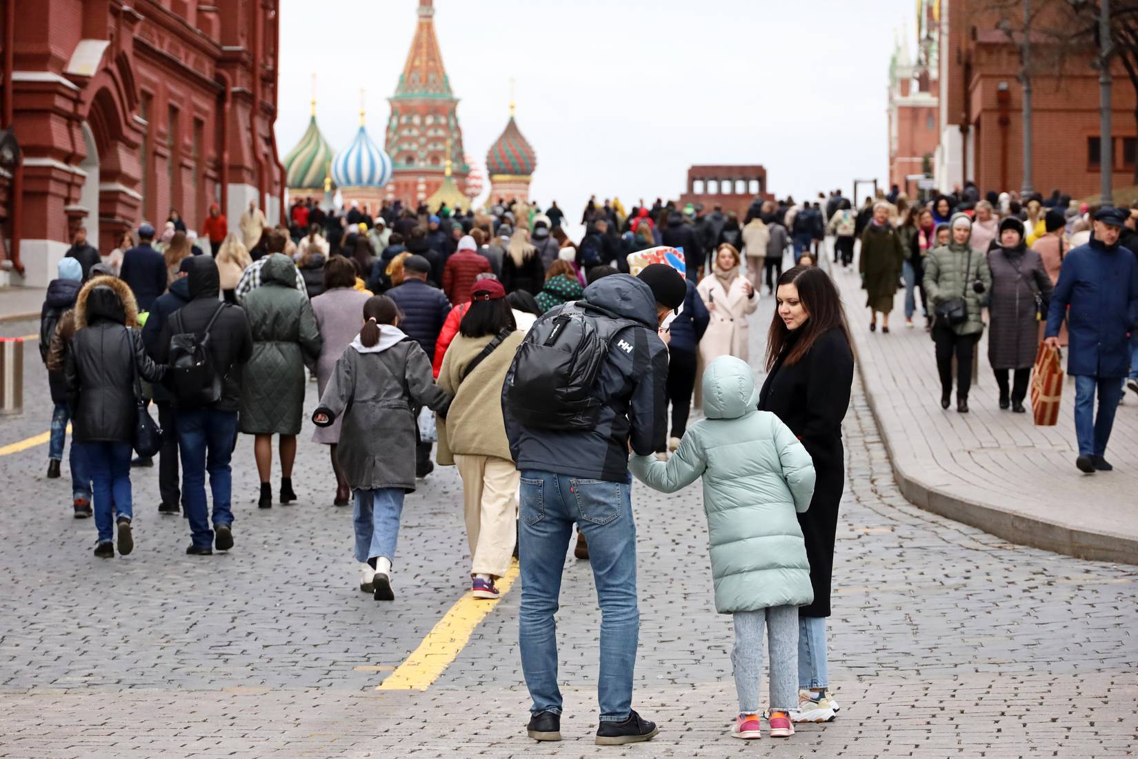 A crowd of people walking in Red Square with St. Basil Cathedral in the background in Moscow, Russia