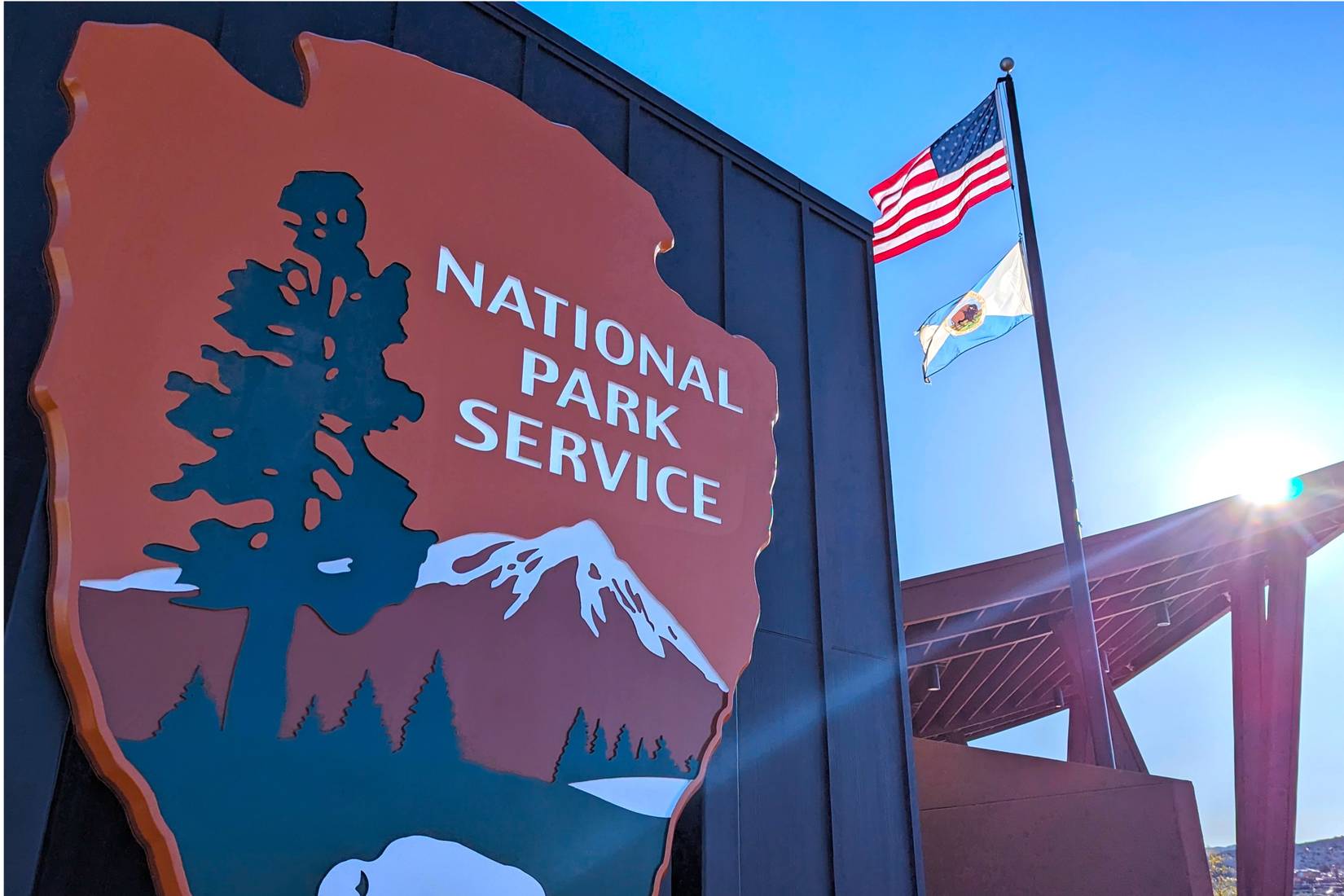 National Park Service sign on the front of Joshua Tree Visitor's Center with American flag in background