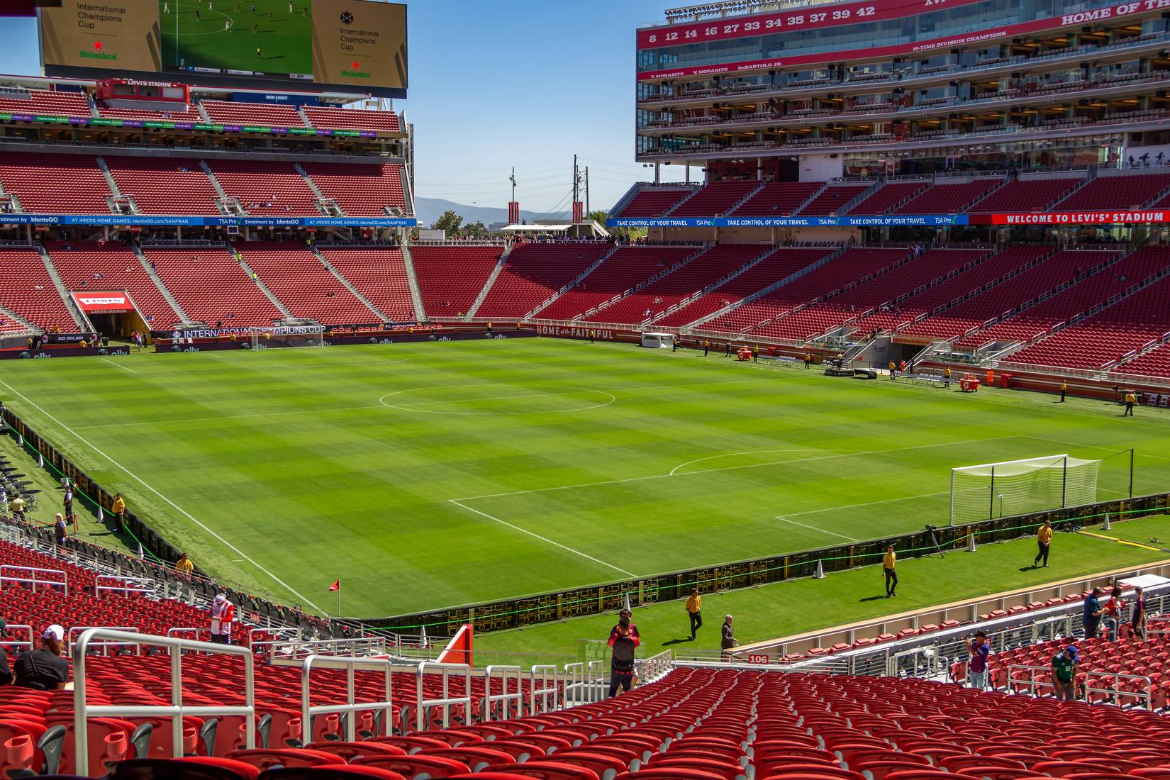 A wide view of Levi's Stadium in Santa Clara featuring a green football field, and red seats for spectators