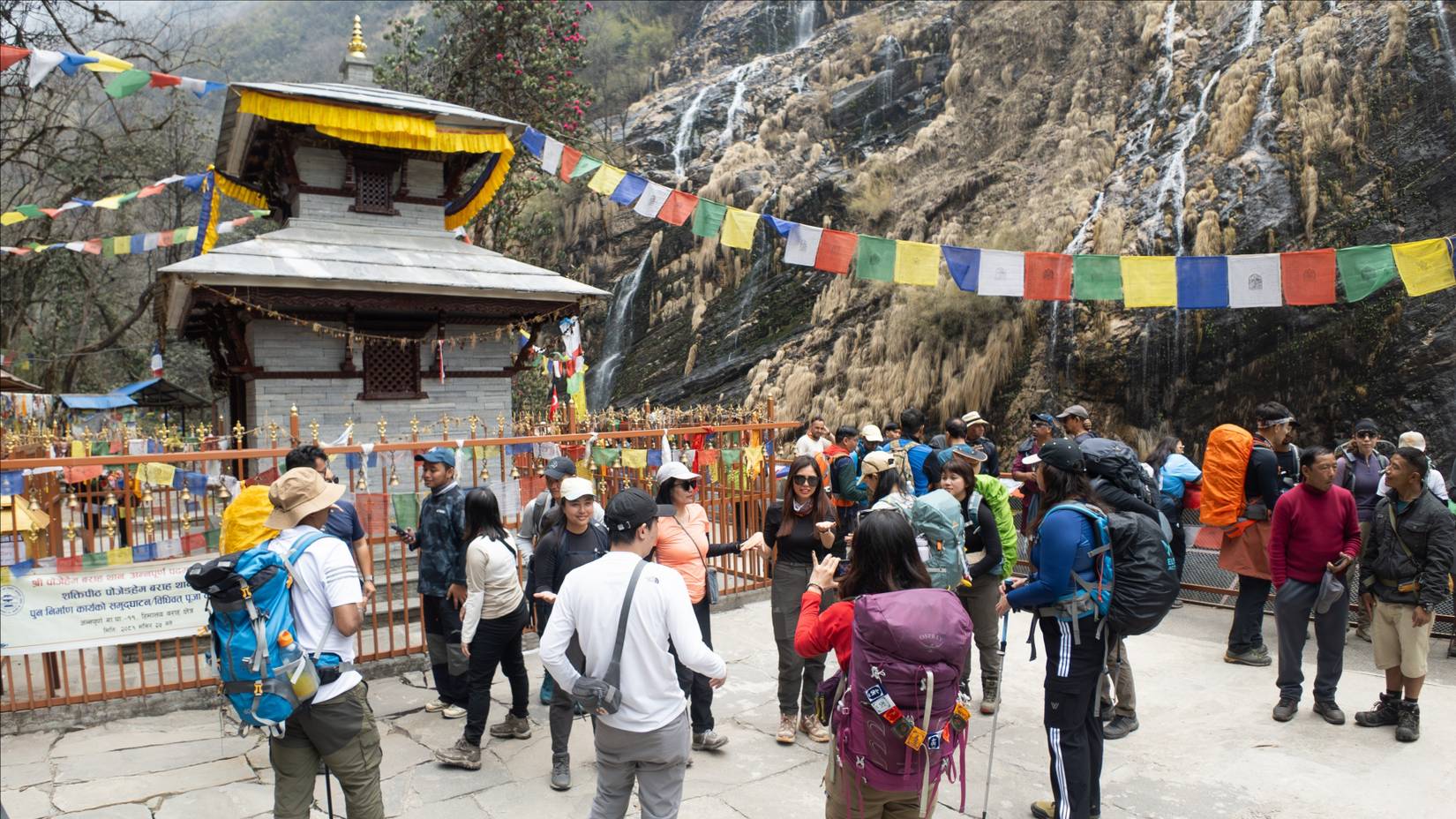 Tourists taking photos at the Barahi Waterfall Temple viewpoint while hiking to Annapurna Base Camp in Ghandruk, Nepal