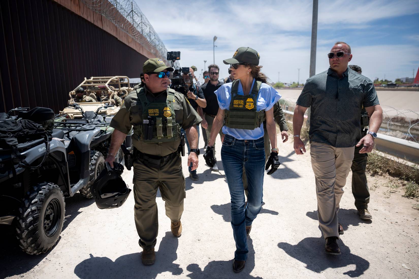 Department of Homeland Security (DHS) Secretary Kristi Noem with Border Patrol federal agents near the U.S.-Mexico Border Wall in El Paso. An all-terrain vehicle (ATV) can be seen next to the wall.