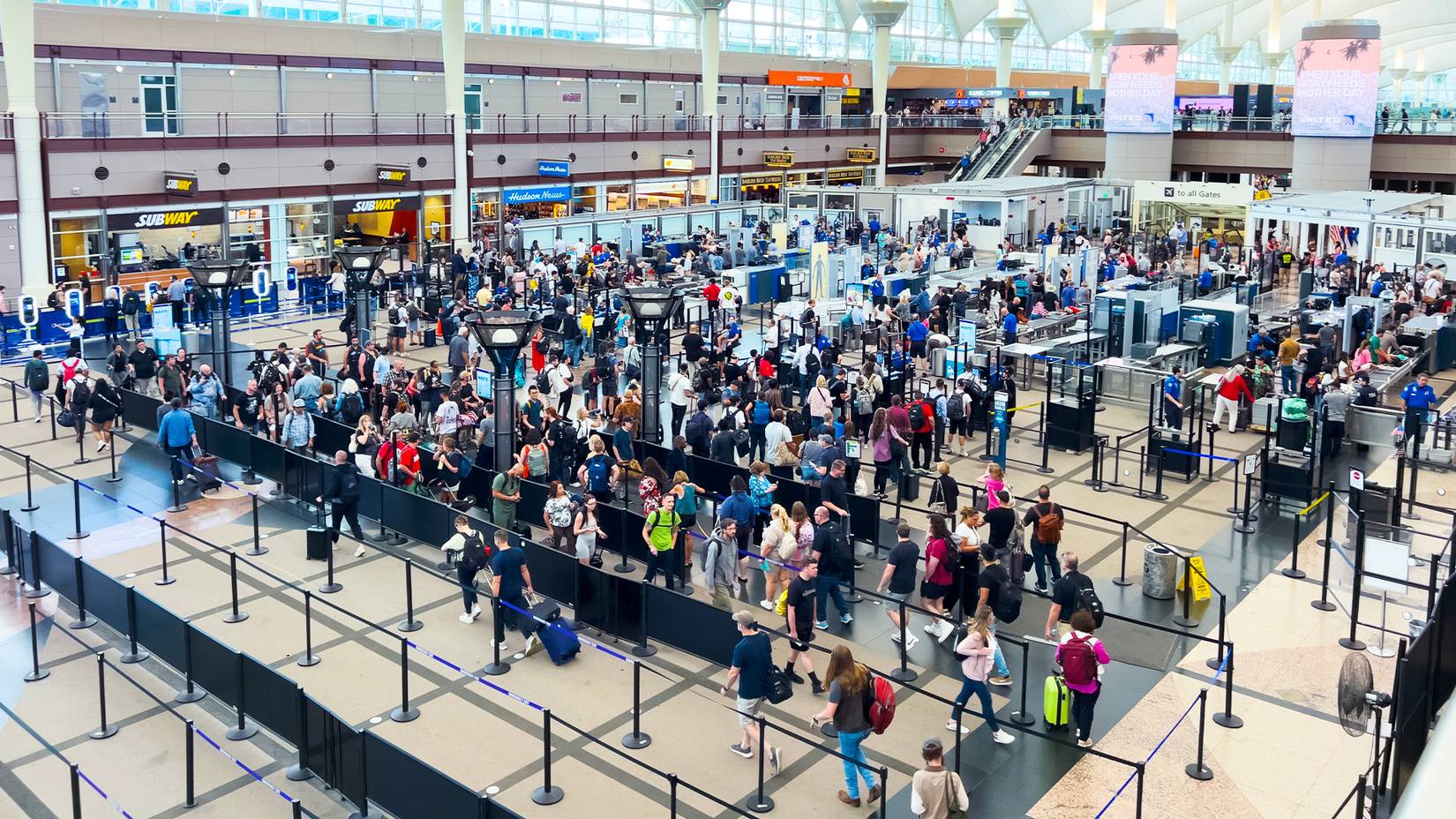 Crowded TSA checkpoint with long, winding lines in the central area of an airport