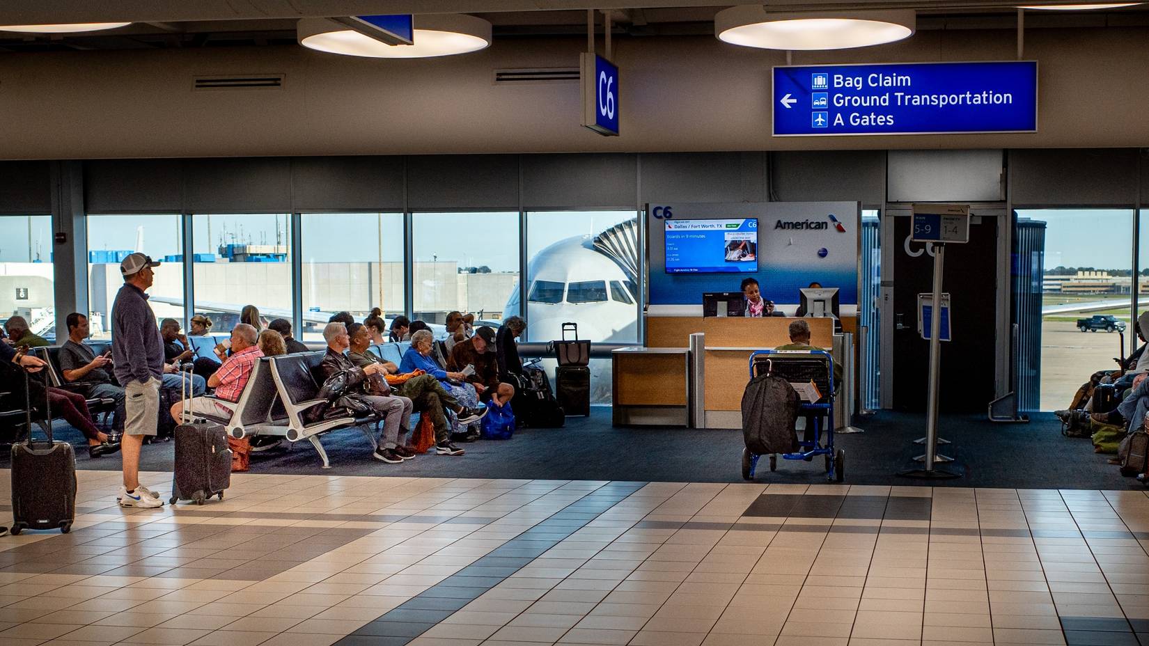 Pasajeros esperan para abordar un vuelo de American Airlines en la puerta de un aeropuerto de EE. UU.