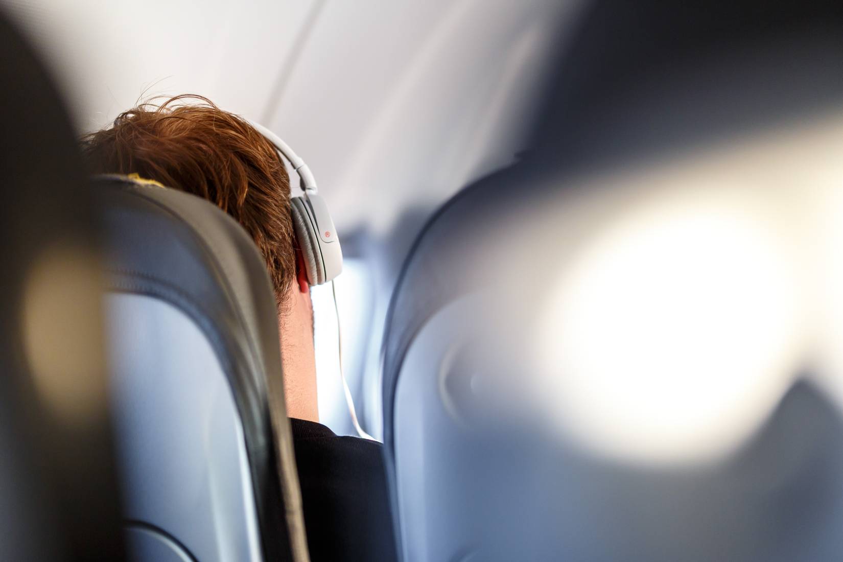 A passenger wearing headphones on a commercial airplane flight