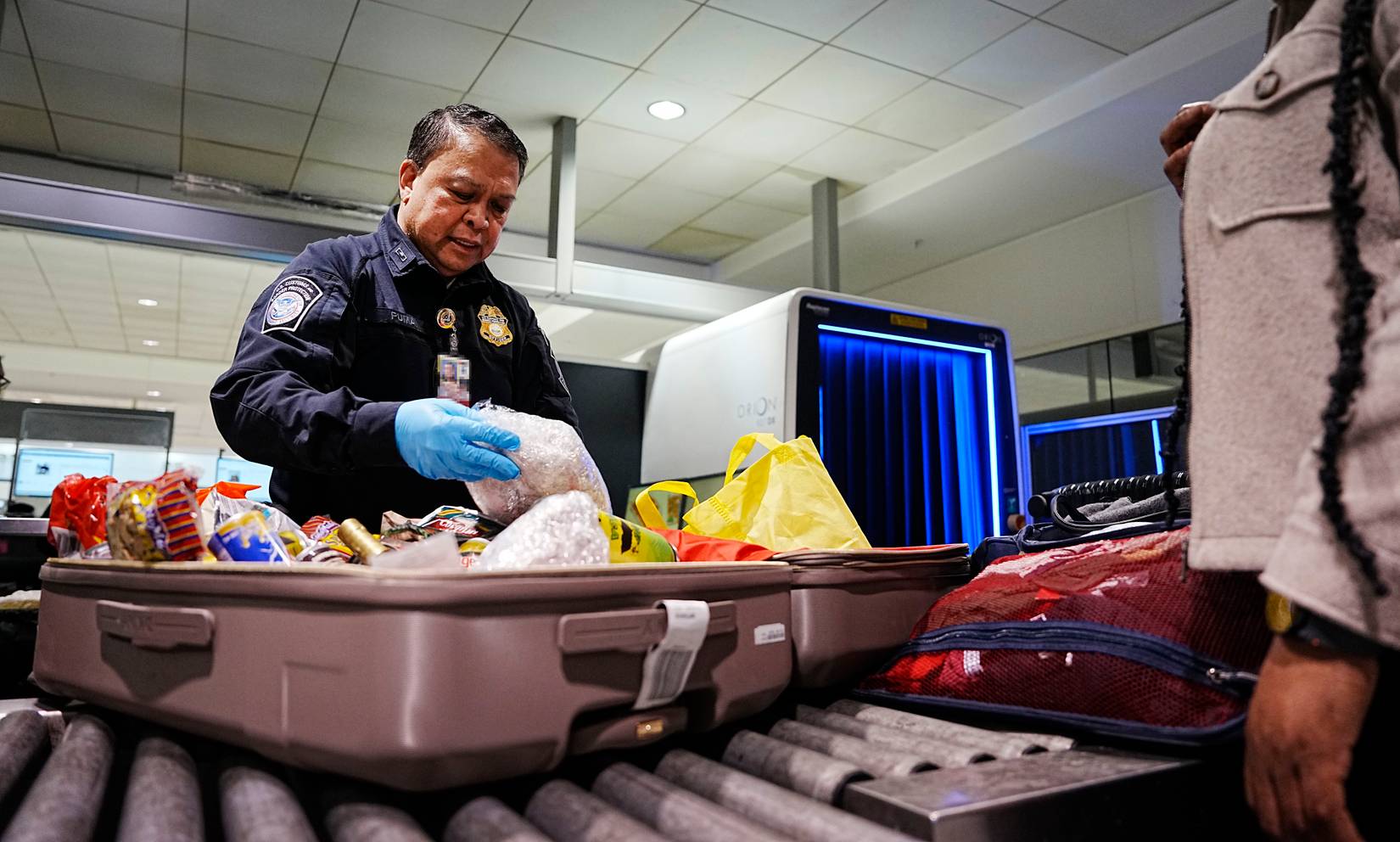 A U.S. Customs and Border Protection (CBP) officer inspecting passenger luggage at a U.S. airport
