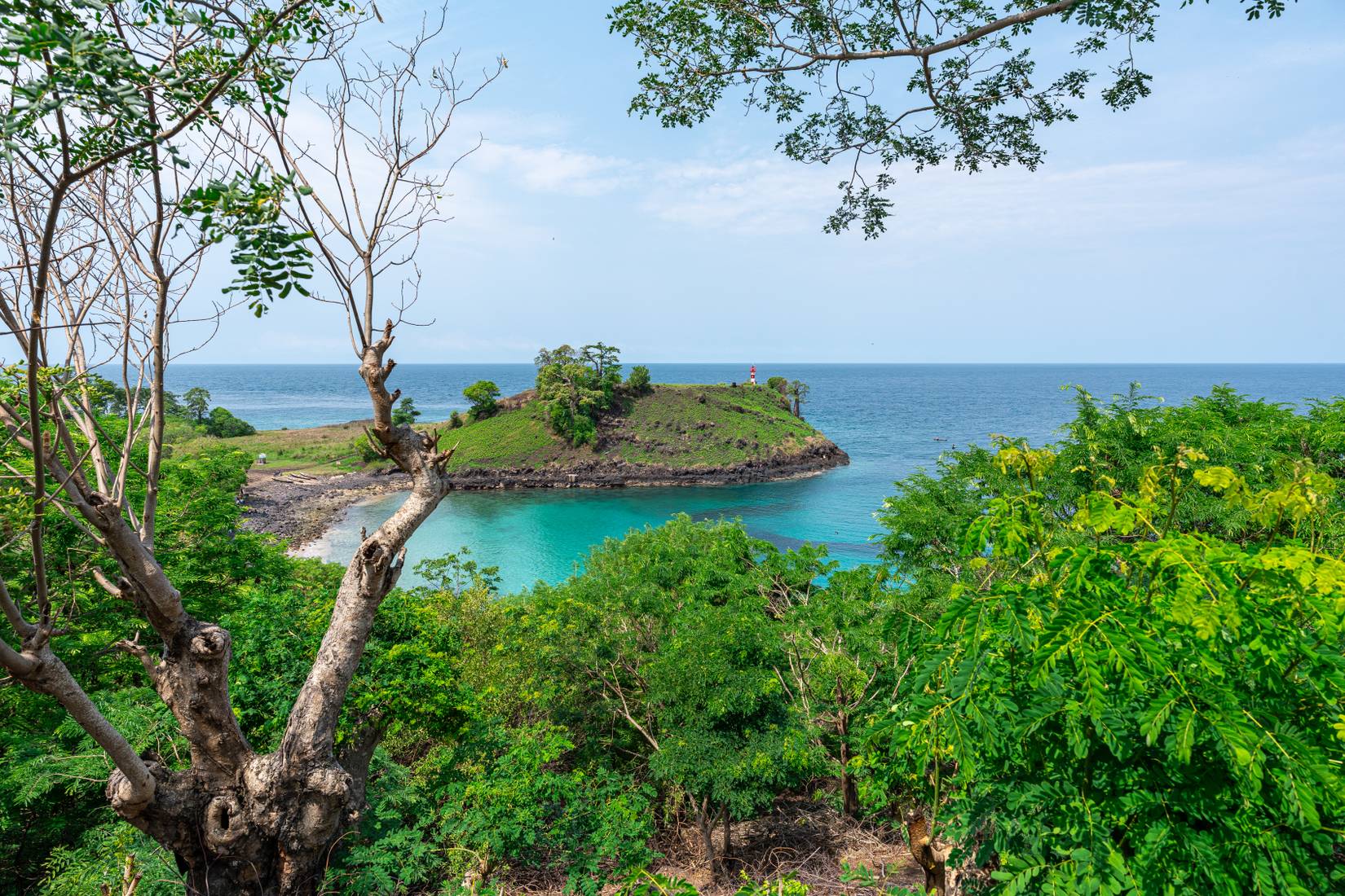 Pemandangan pantai, dengan mercusuar terlihat dari kejauhan di SÃ£o TomÃ© dan PrÃncipe