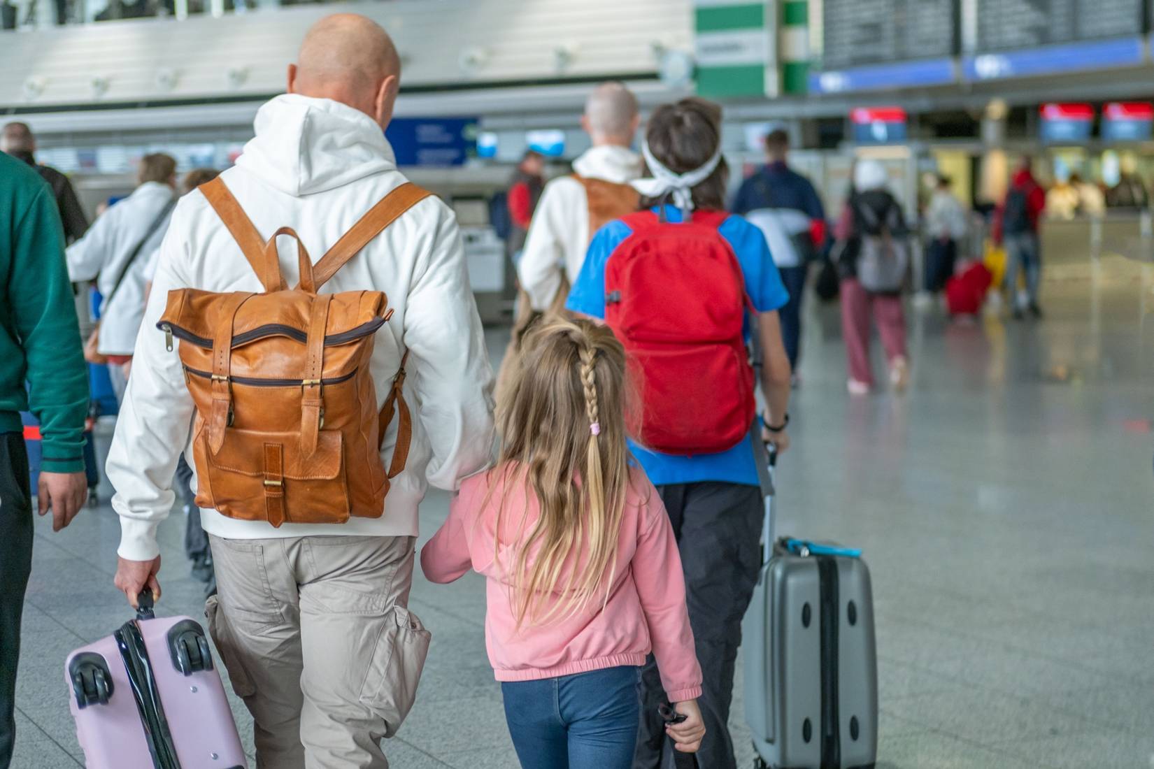 Travelers family with children, suitcases, and backpacks in airport terminal