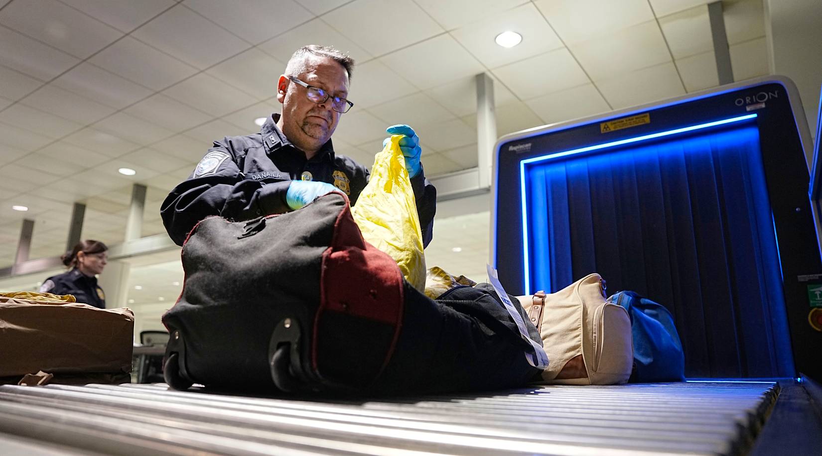 U.S. Customs and Border Protection (CBP) officers inspecting passenger bags at a U.S. airport