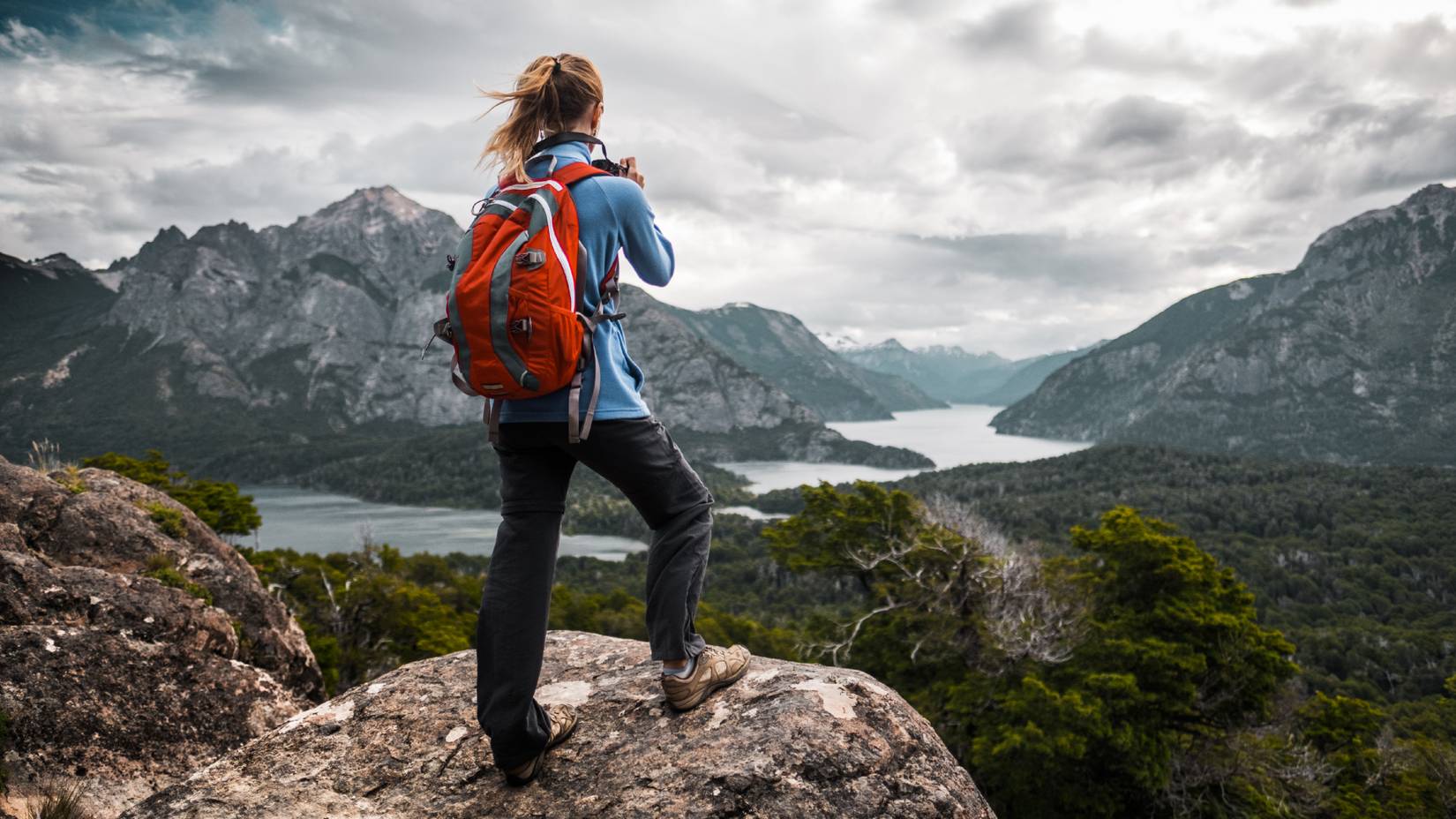 Excursionista tomando fotografías del valle con montañas y lagos en la Patagonia, Argentina