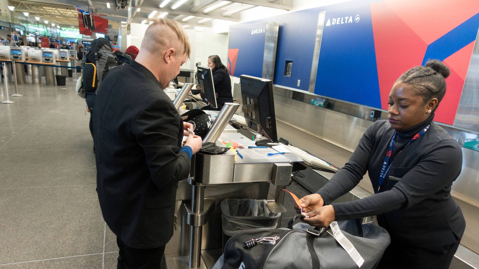 Delta Air Lines ticket agent checks in an international traveler and his luggage at Minneapolis St. Paul International Airport
