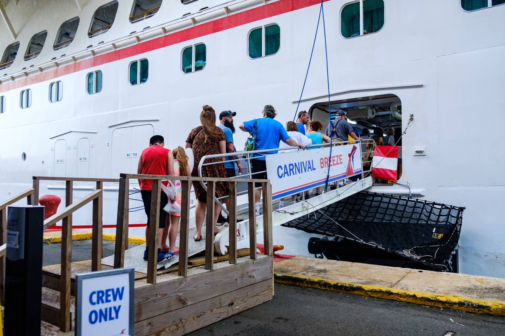 Guests are waiting in a queue at the gangway to get to the Carnival Breeze cruise ship.
