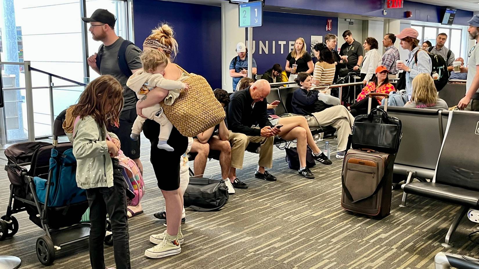 Passengers line up to board a United Airlines flight during the busy summer travel season in Boston Logan International Airport (BOS)