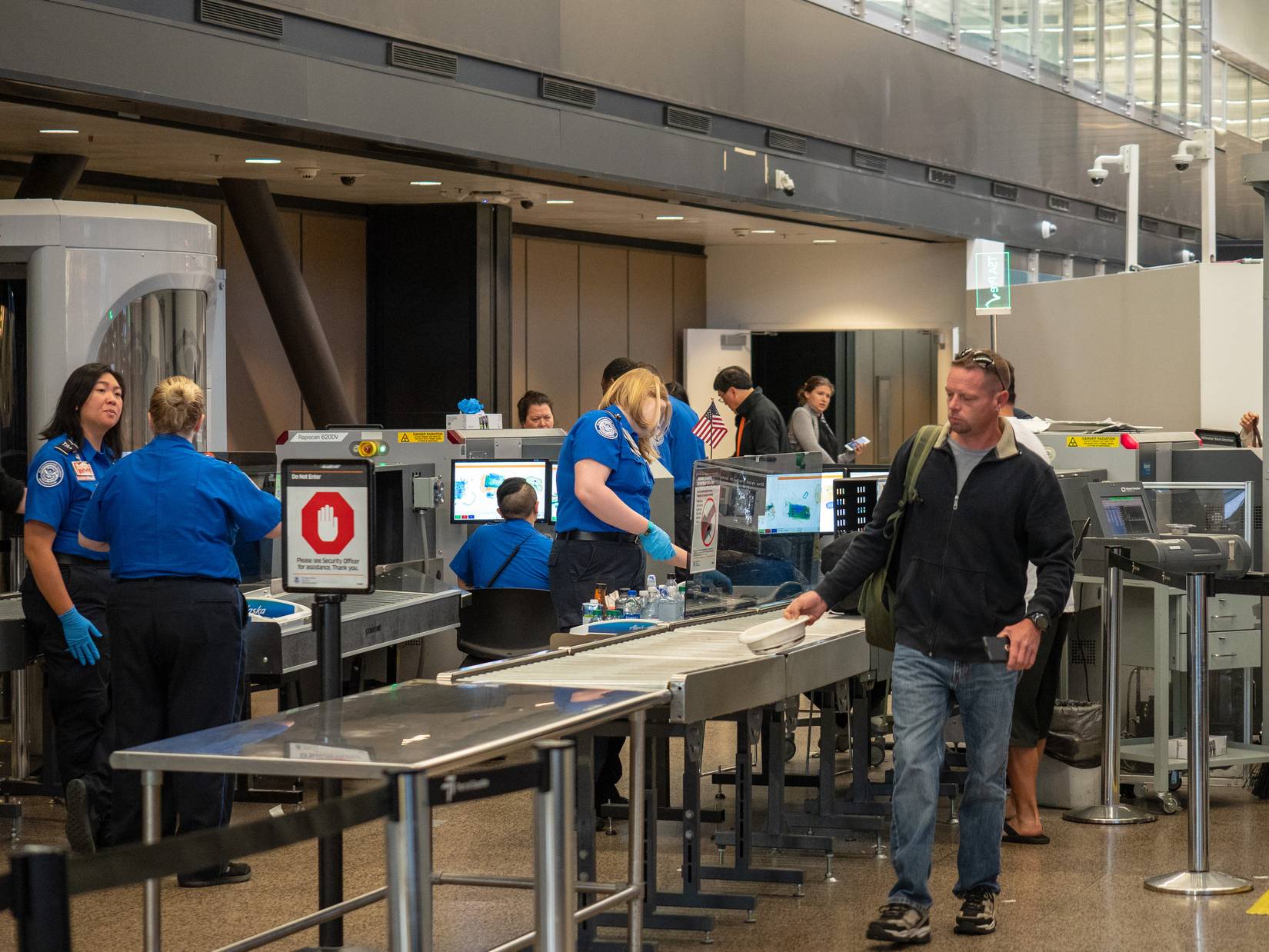 Transportation Security Administration (TSA) officers screening passengers at a U.S. airport security checkpoint