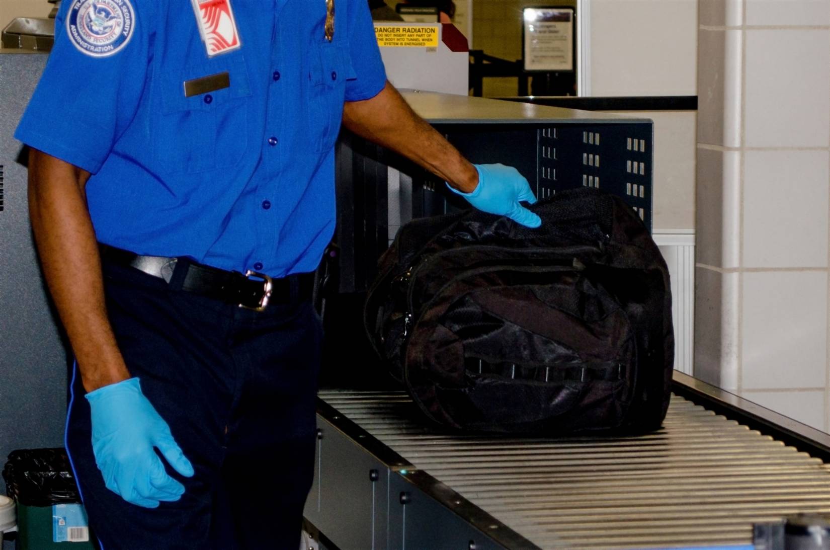 TSA (Transportation Security Administration) officer with a bag at a U.S. airport security checkpoint