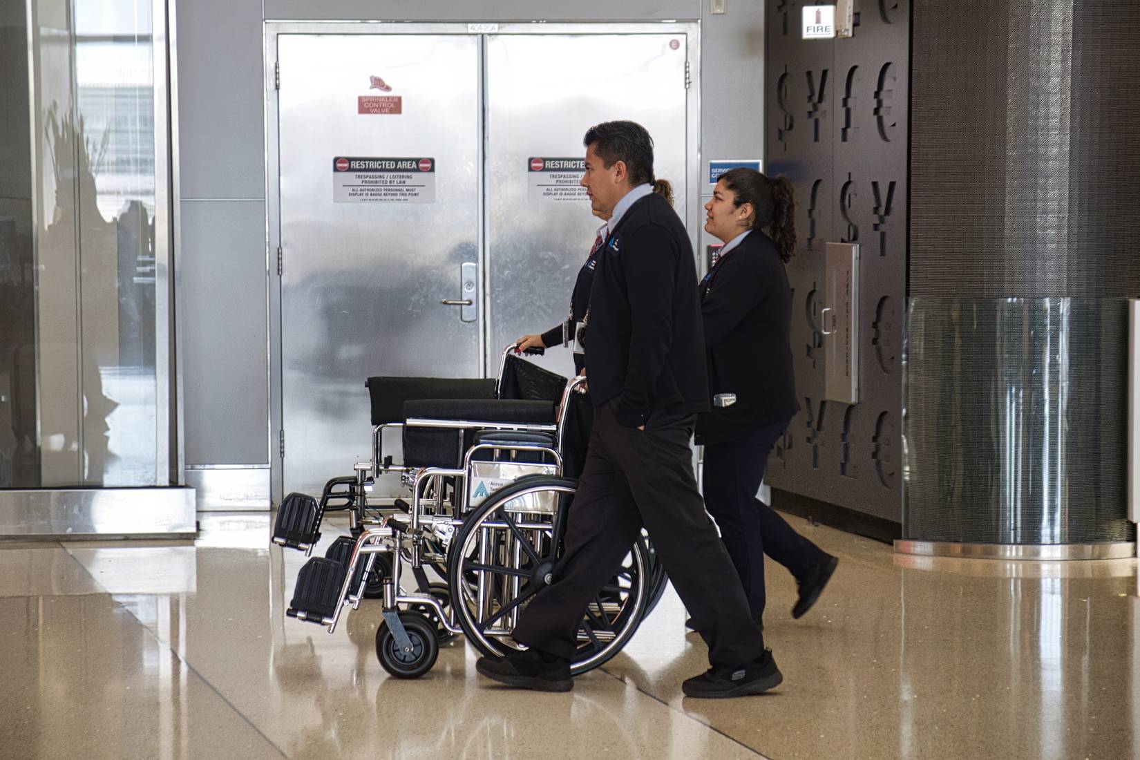 Airport employees at Los Angeles International Airport pushing two wheelchairs