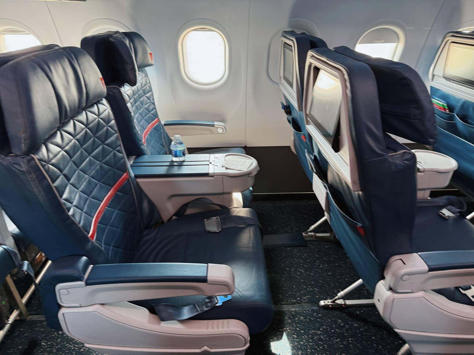 First class seats on airplane shown. Two seats with window in the background on plane