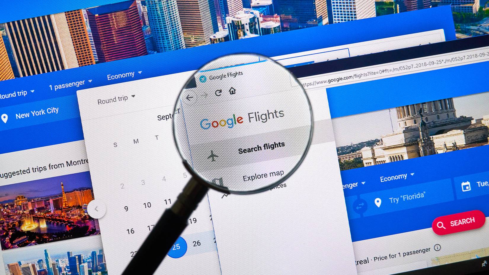 Google flights website open on a computer with a magnifying glass held up in front of the screen