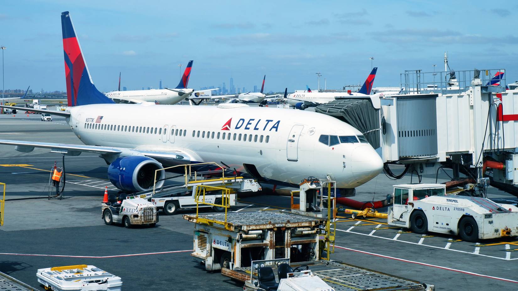 With the New York City skyline in the distance, a Delta Air Lines plane is prepared for its next flight at John F. Kennedy International Airport.