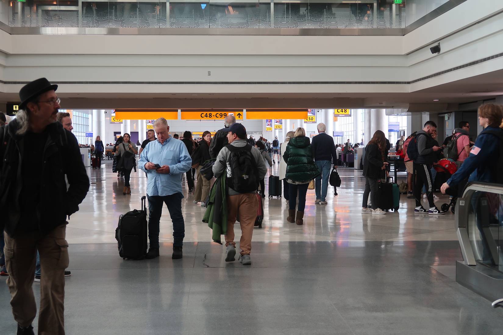 Crowds of people walk to the gates and baggage claim at Denver International Airport