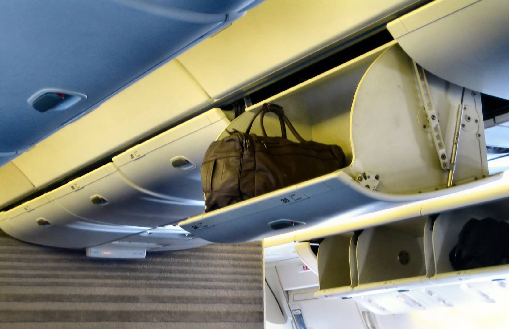 Reenactment of American Airlines passenger with open bin on flight.