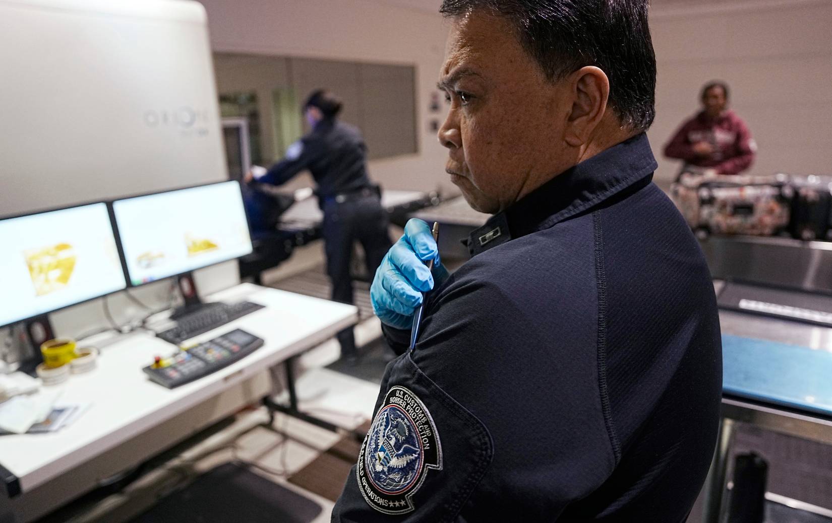 U.S. Customs and Border Protection (CBP) officers checking international arriving travelers' documents and luggage at an American airport