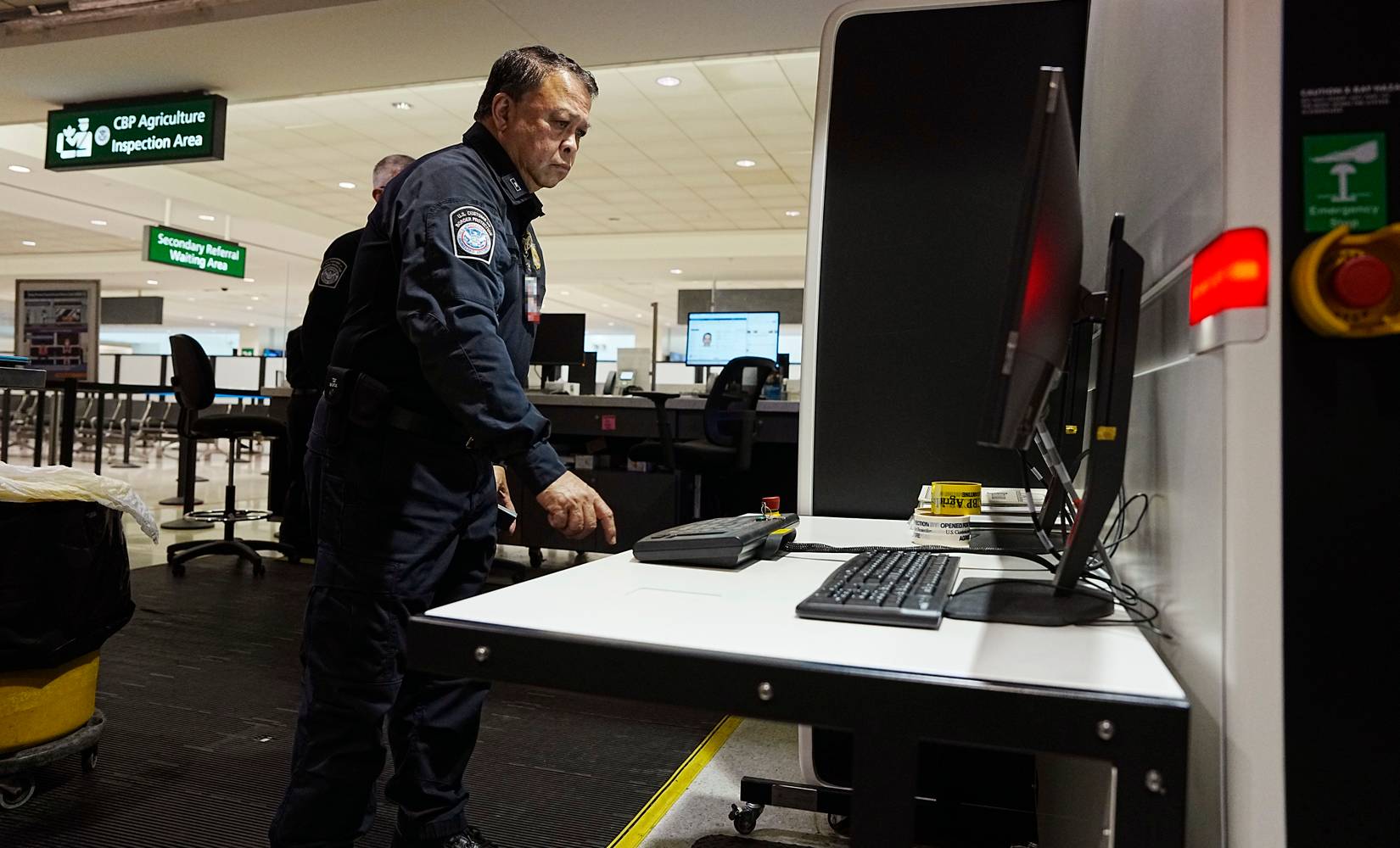 U.S. Customs and Border Protection (CBP) officers checking travelers' documents and luggage at an American airport