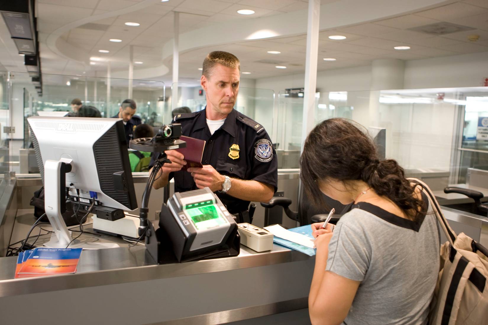 U.S. Customs and Border Protection (CBP) officers processing travelers' passports at an American airport