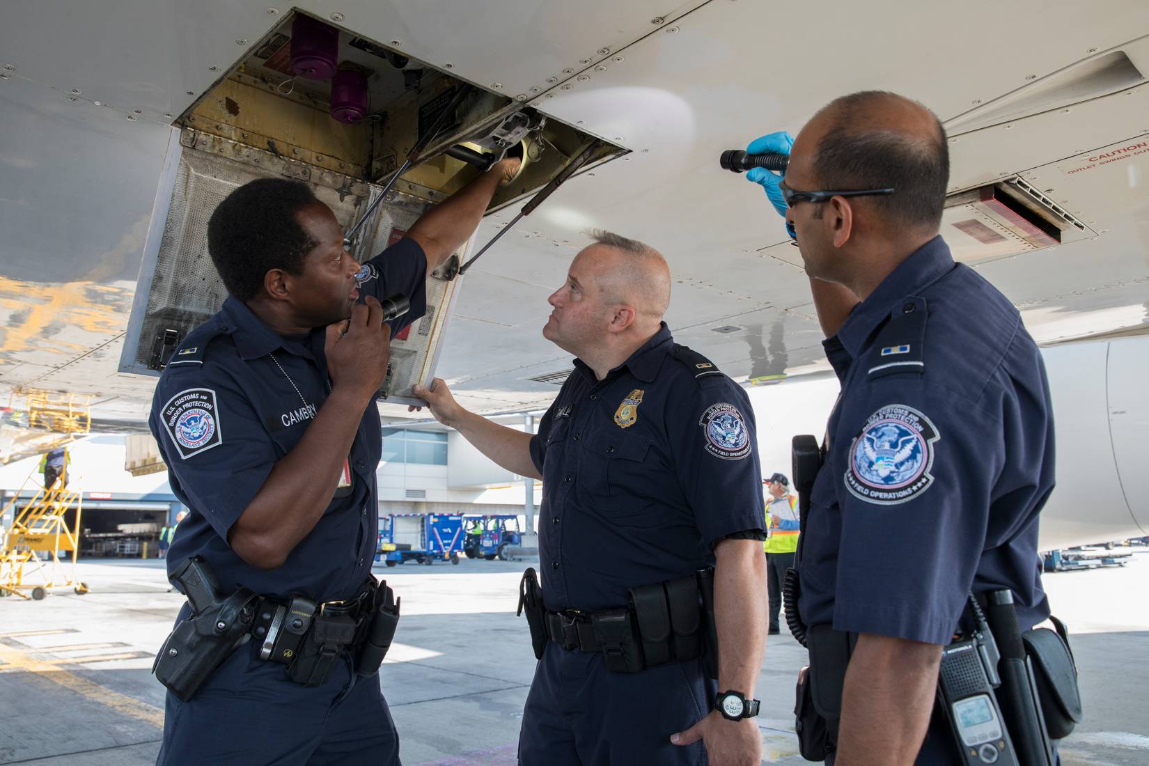 U.S. Customs and Border Protection (CBP) searching an aircraft's undercarriage at a US airport