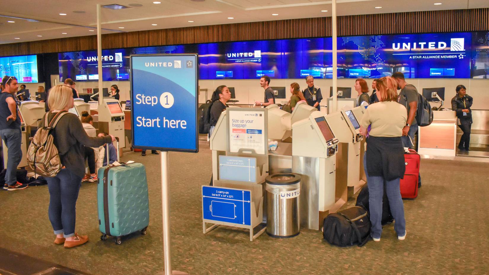 Passengers using United Airlines' self-service check-in kiosks