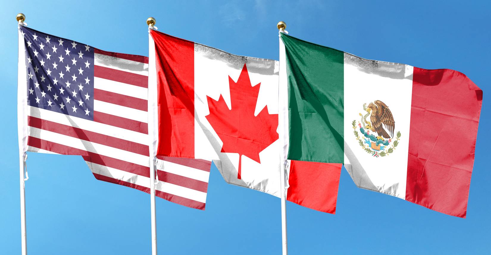 Flags of the U.S., Canada, and Mexico against the cloudy sky
