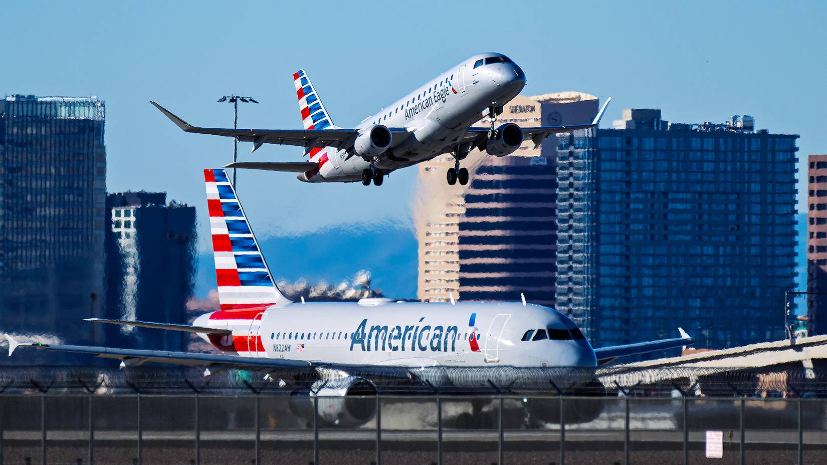 An American Airlines plane takes off over a plane on the runway