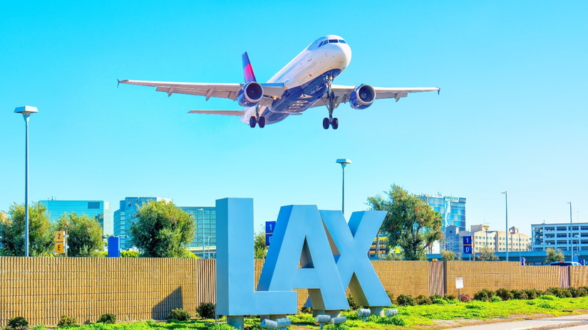 Delta Airlines aircraft in mid-flight, soaring above the iconic LAX sign at Los Angeles International Airport