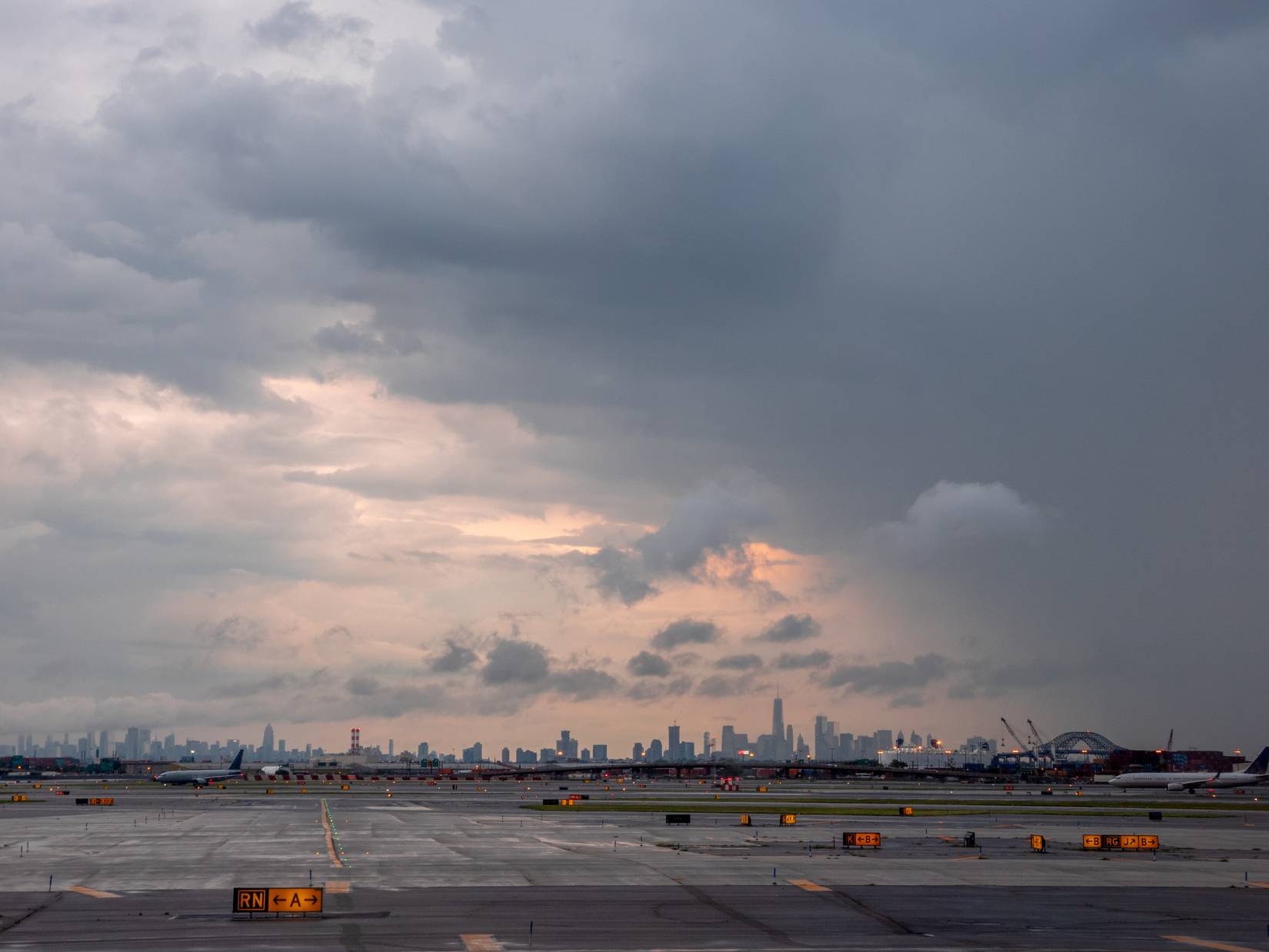 Thunderstorm looming over Newark Airport at sunset, delaying flights.