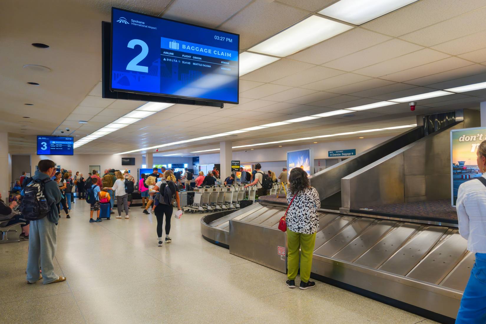 Travelers wait for their luggage at the carousel in the baggage claim area of the Spokane International Airport.