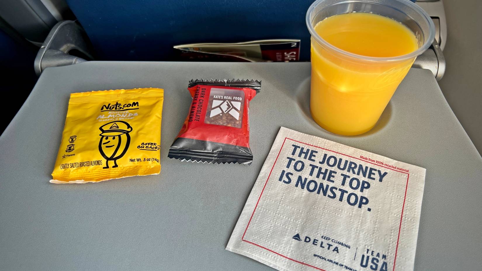 Snacks and orange juice served on a Delta Air Lines flight, on a pull-down seat table