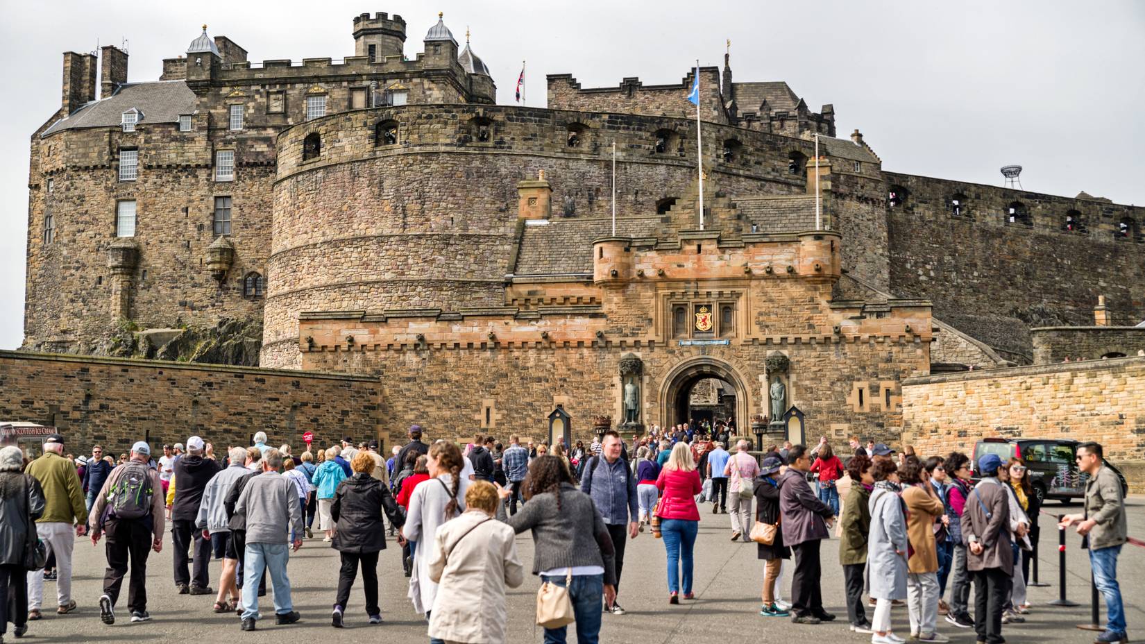 Tourists walking and gathering in front of Scotland's historic Edinburgh Castle, a landmark and popular travel destination in the United Kingdom